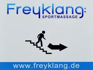 Schild mit der Aufschrift "Freyklang Sportmassage" und einem Männchen auf einer Treppe mit Pfeil als Richtungsweiser.