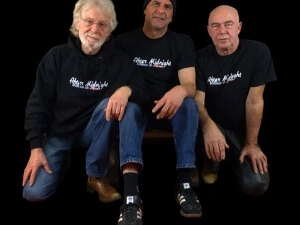 Drei Rockmusiker, die schwarze Hoodies und T-Shirts tragen mit ihrem Bandlogo "After Midnight" auf der Brust.