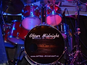 Schlagzeug mit Base-Drum, die Folienbeschriftet ist - Holz-Hintergrund mit Band-Logo.