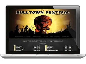 Laptop mit Festival-Website des Bulltown-Festivals - dunkeles Webdesign im Retro-Stil mit angestrahlter Inka-Figur und silhouettenhaften Rockkonzert im Vordergrund.