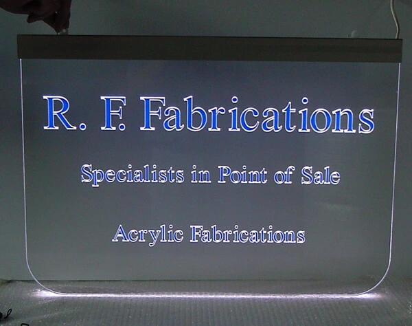 Transparentes Acrylglas-Schild mit eingefräster Schrift, die mit blauer Folie unterlegt ist und durch einen LED-Kantenstrahler zum Leuchten gebracht wird.