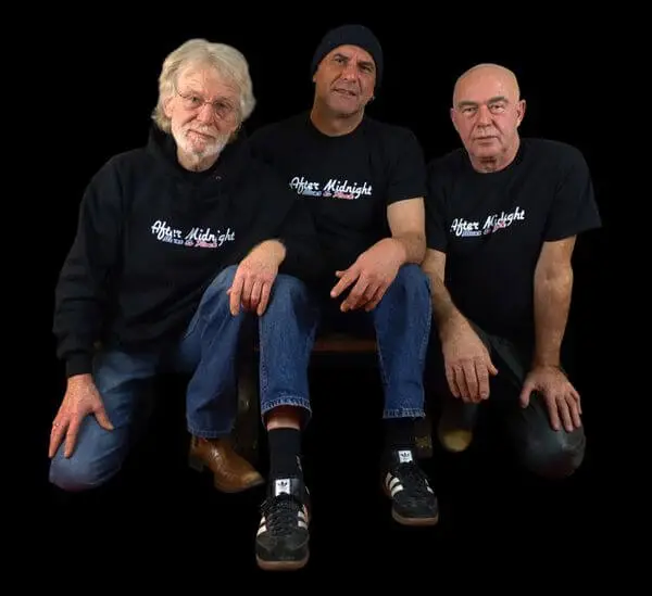 Drei Rockmusiker, die schwarze Hoodies und T-Shirts tragen mit dem Bandlogo "After Midnight" auf der Vorderseite.